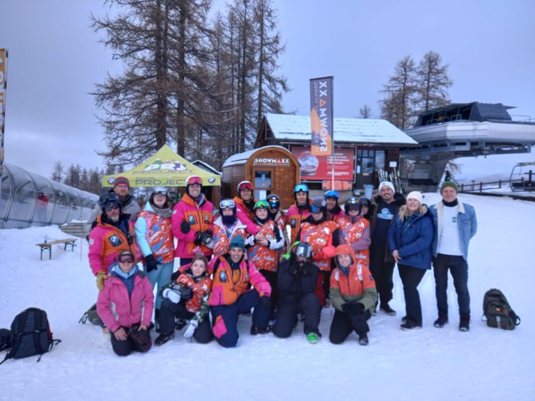 Students, staff and instructors on the slopes smiling for a group photo