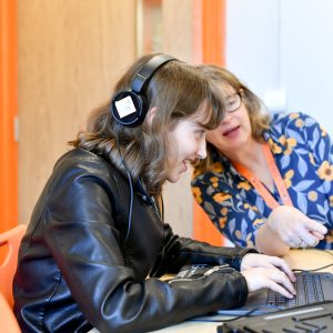 A NCW Sixth Form student smiling whilst working on a laptop during a lesson