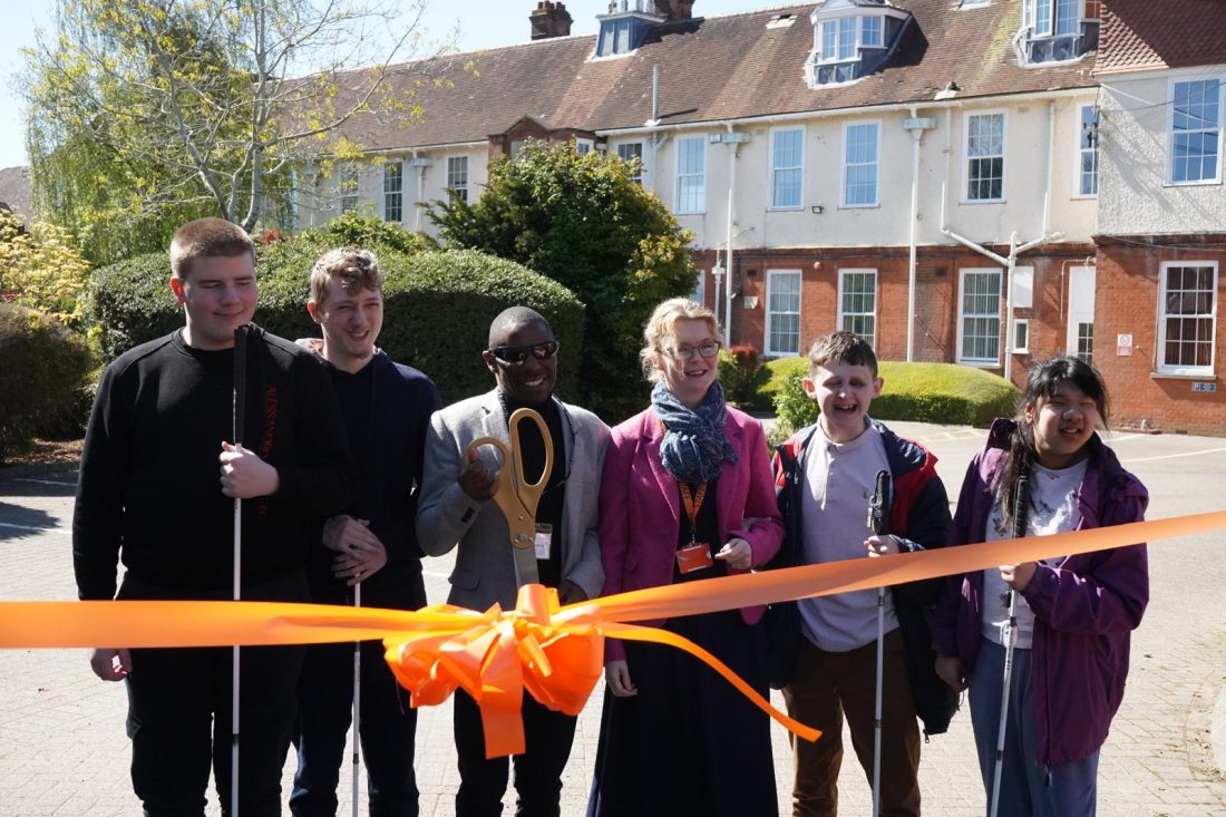 Darren Harris, Mrs Perks and students smiling by the ribbon crossing