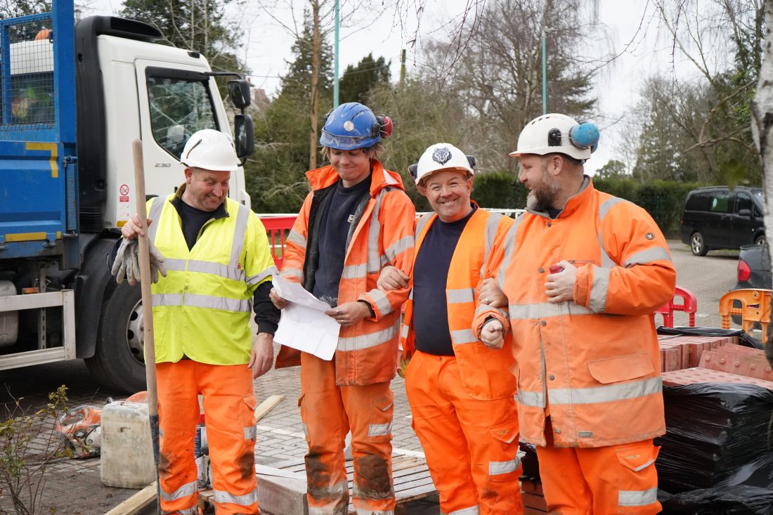 Photo of workpeople in high viz smiling mid work