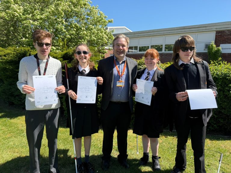 Mr Painter and four students pose for a photo holding their certificates on the lawn at NCW