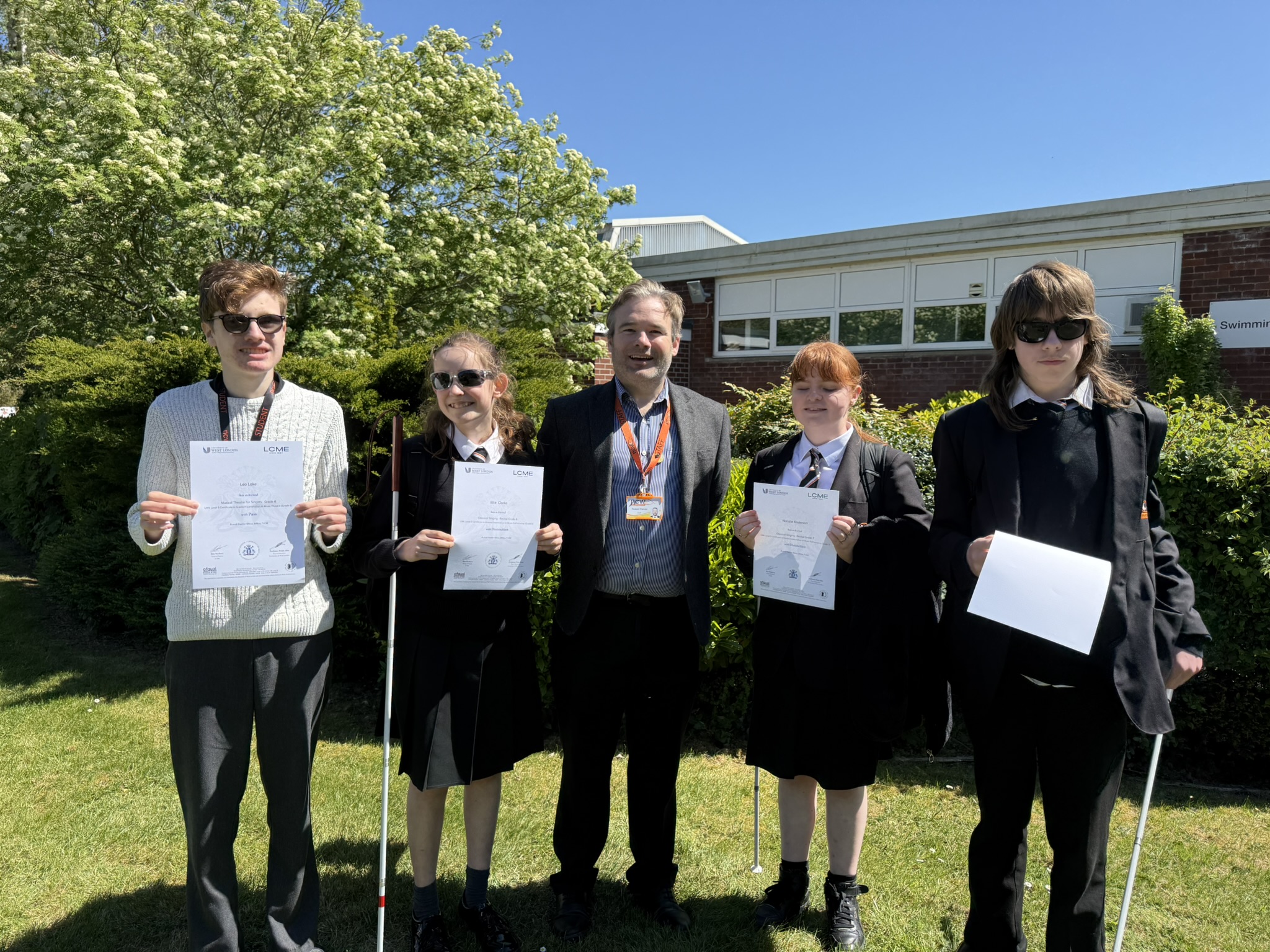 Mr Painter and four students pose for a photo holding their certificates on the lawn at NCW