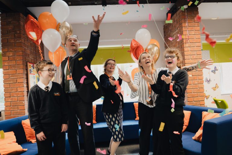 Staff and students throwing confetti and smiling