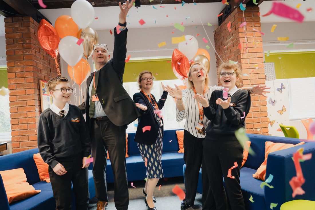 Staff and students throwing confetti and smiling