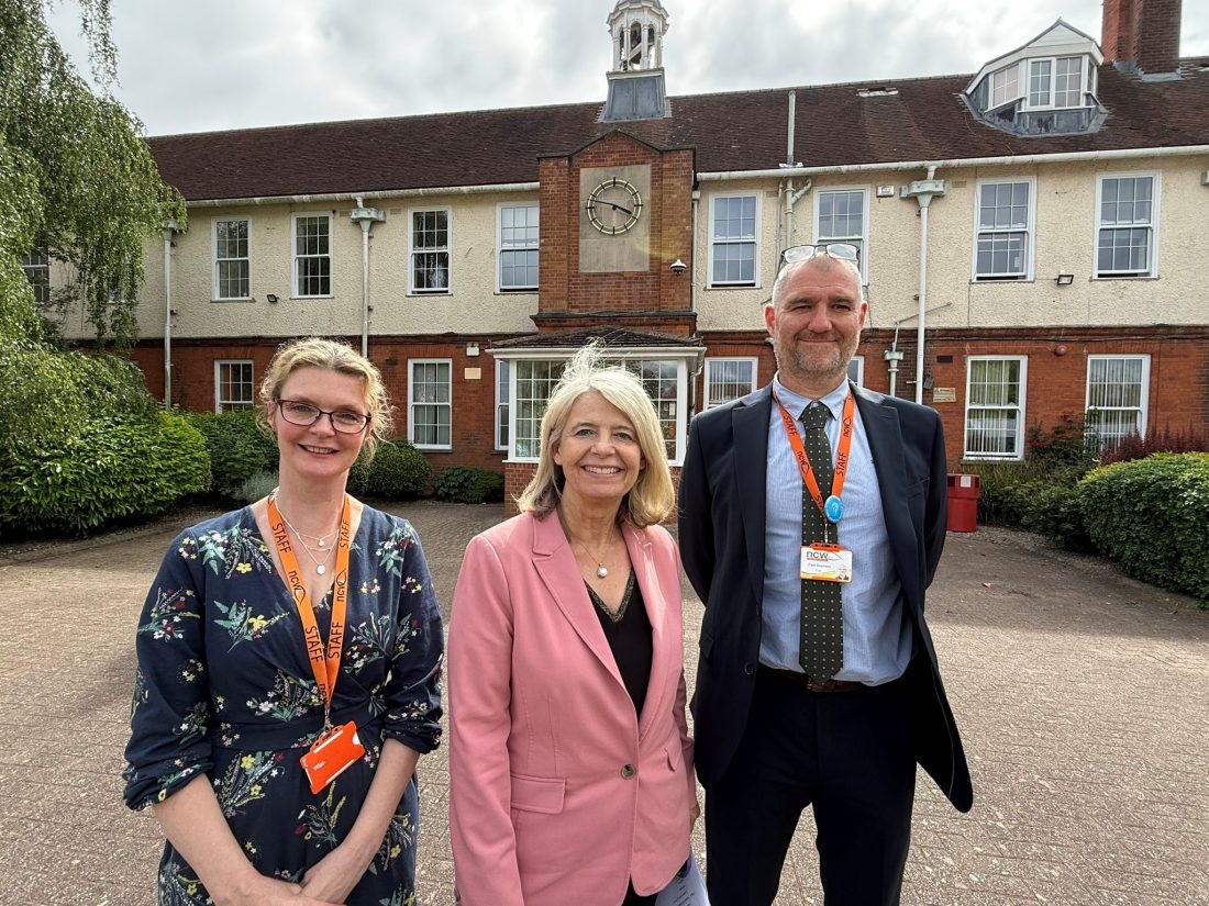 Rachel Perks, Dame Harriett Baldwin and Paul Stephens smiling outside of the main school building