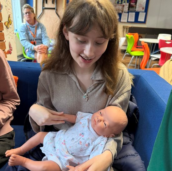 Photo of a student holding a baby doll