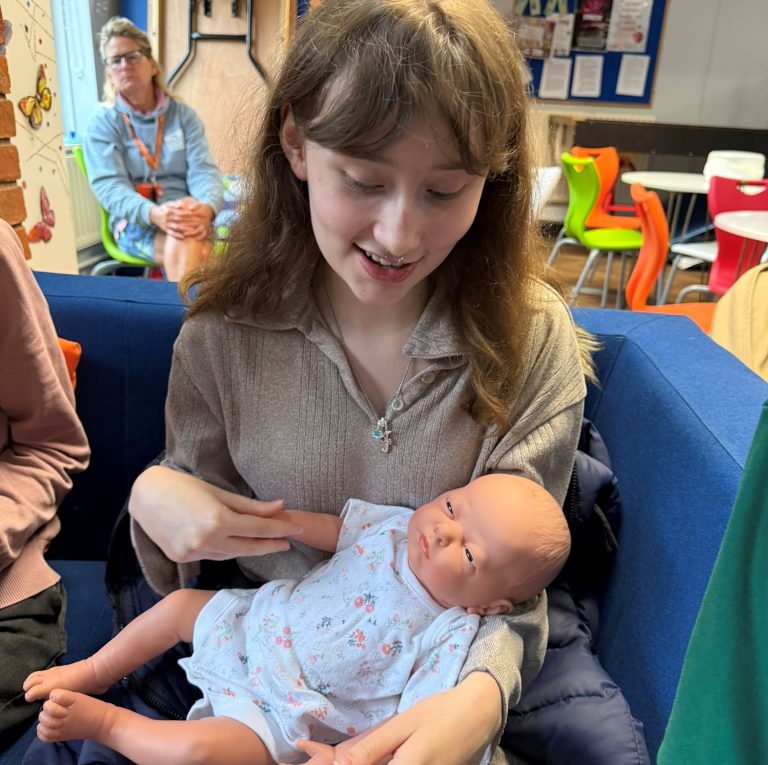 Photo of a student holding a baby doll