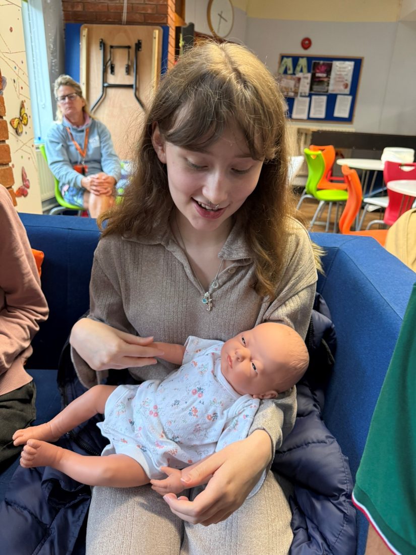 Photo of a student holding a baby doll