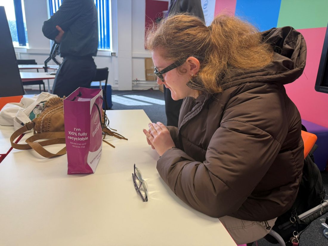 A student wearing glasses and reading a piece of paper
