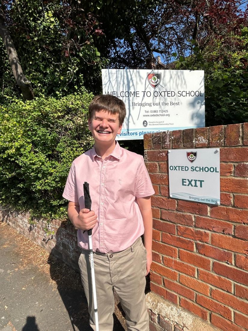 George standing outside the school smiling holding his cane