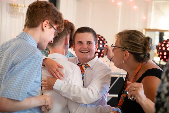 Photo of three students smiling and hugging